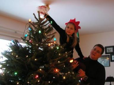 Daddy helps Bethan place the angel on the tree top